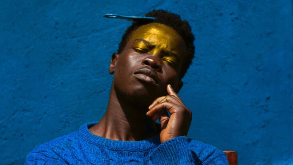 Photo of a man in blue sweater in front of a blue wall