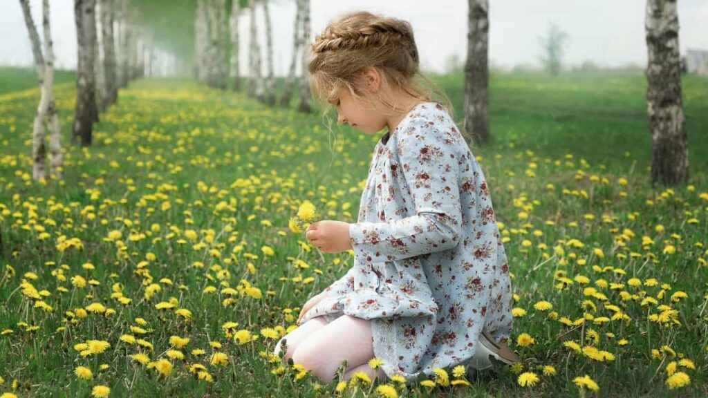 Photo of a young girl picking flowers in a field